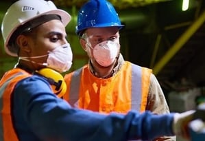 Manufacturing professionals wearing hardhats and face masks.